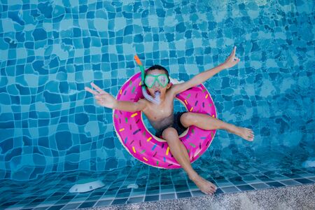 View of boy with swim ring floating in the swimming poolの写真素材