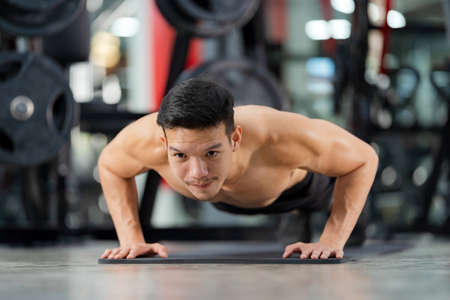 Sporty man training with a heavy barbell at the gym