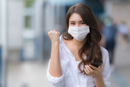 Portrait of young woman with smiley face wearing face mask protective walks in a cityの写真素材