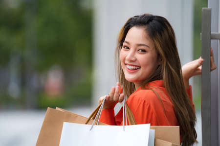 Outdoors portrait of Happy woman holding shopping bags and smiling face at the mallの写真素材