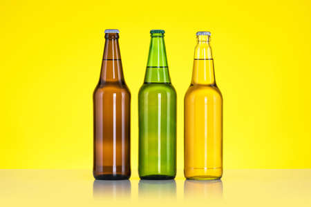 Group of Three bottles of beer isolated on yellow background, Close up
