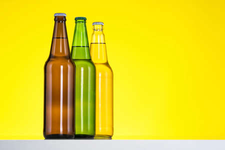 Group of Three bottles of beer isolated on yellow background, Close upの写真素材