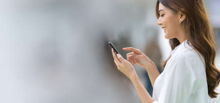 Outdoors portrait of Happy young woman using a phone in the cityの写真素材