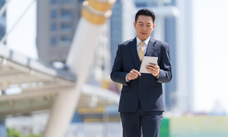 Portrait of successful businessman with arms crossed standing in front of modern office buildingsの写真素材