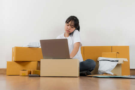 Asian woman working with calculator, Selling online ideas concept, Online seller business shop at homeの写真素材