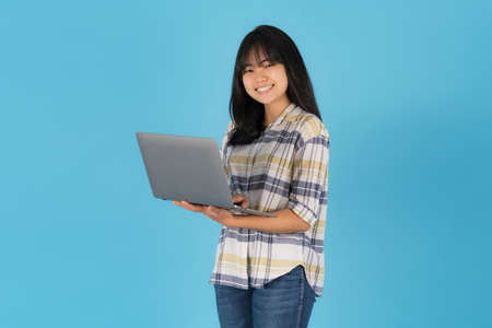 Happy smiling asian girl with using laptop on pink backgroundの写真素材