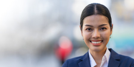 Portrait of smiling business woman while standing in front of modern office buildingsの写真素材