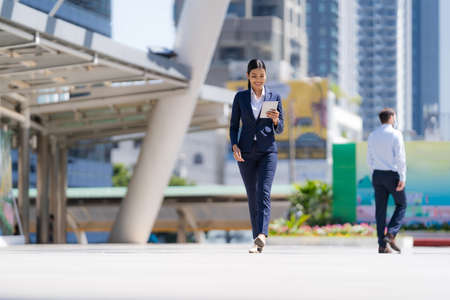 Portrait of smiling business woman while standing in front of modern office buildingsの写真素材