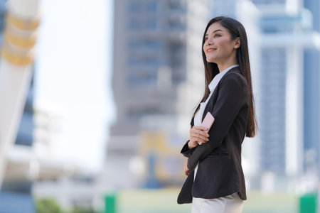 Portrait of smiling business woman while standing in front of modern office buildingsの写真素材