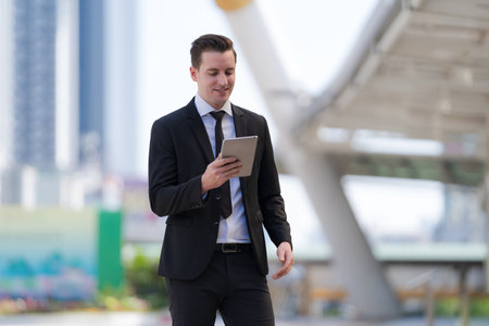 Close up of Smiling businessman standing in front of modern office buildingsの写真素材