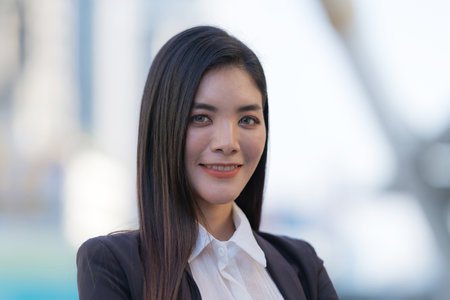 Portrait of smiling business woman while standing in front of modern office buildingsの写真素材