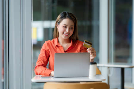 Beautiful young woman sitting at a coffee shop with drinking coffeeの写真素材
