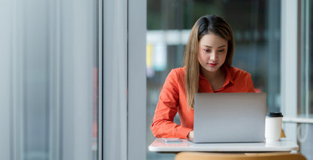 Woman in white t-shirt and blue jeans using laptop sitting on a floor outside in the city street background, Summer dayの写真素材