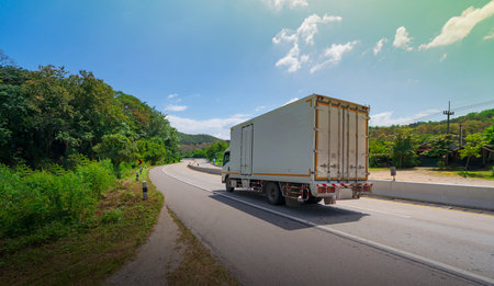 White truck driving on the asphalt road in rural landscape at morningの写真素材