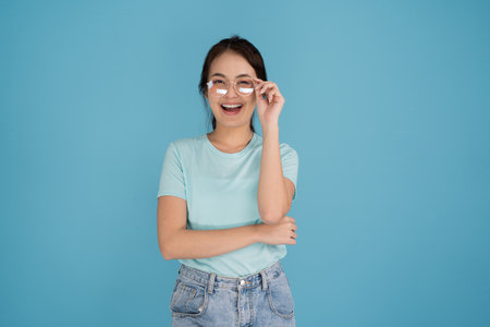 A woman in a blue shirt is smiling in various poses, looking at the camera on a blue background.の写真素材