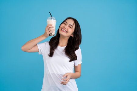 Asian girl holding a cup of pearl milk tea With a smile, fun and happiness on a blue background.の写真素材