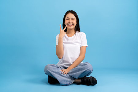 Beautiful girl sitting doing various poses On a blue background, sitting, smiling, happy, relaxing, excited, having fun.の写真素材