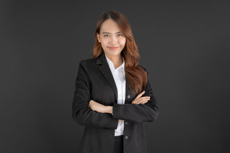 Business woman wearing a black suit Standing with arms crossed and smiling on a black background.の写真素材