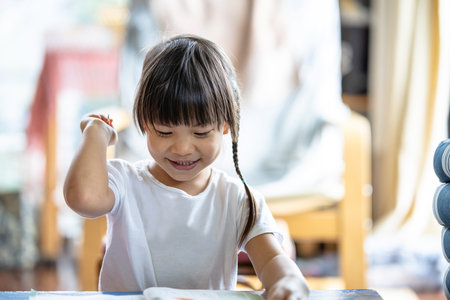 Selective focus of a 3-year-old Asian girl practicing writing and drawing at home with her...