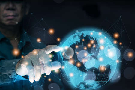 A business man reaching for a virtual globe with lines showing the limitless connections on the...