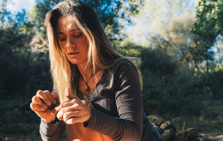 Woman concentrating on making primitive tools in nature