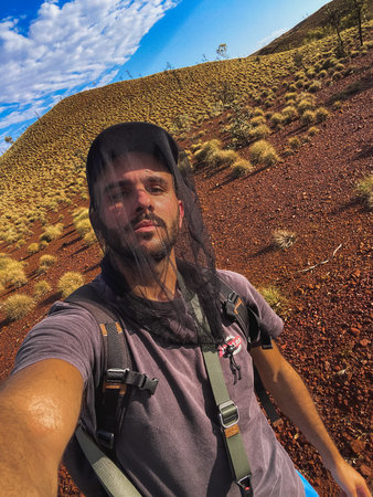 Adventurer taking a selfie wearing a fly net in australian outback