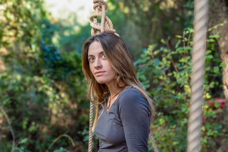 Young woman contemplating in forest swing ropes