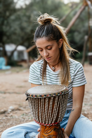 Woman playing djembe drum outdoors finding peace through rhythmの写真素材
