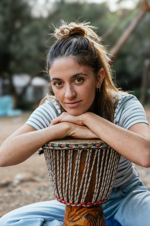 Young woman resting on djembe drum outdoors
