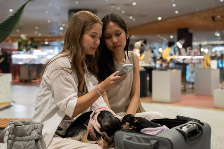 Women friends using smartphone with puppies in shopping mall
