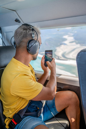 Man taking aerial view video from airplane window