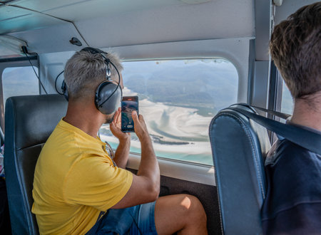 Tourist recording aerial view of whitehaven beach from plane