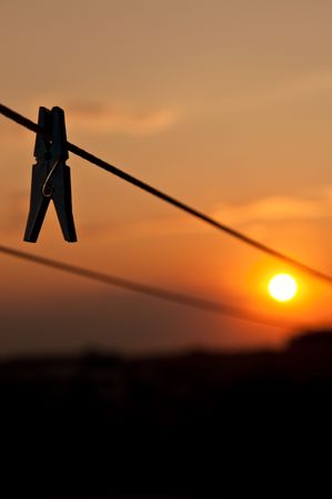 One clothespin weighs on a cord, against an evening sunset