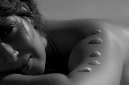 The beautiful woman lies on a beach, on her hand cockleshells lieの写真素材