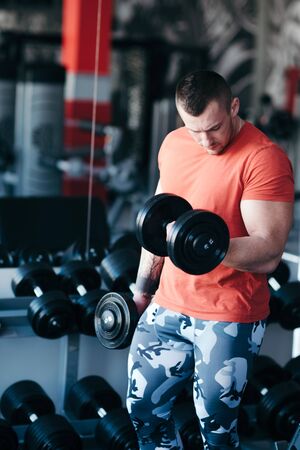 Muscular man training with black dumbbell in the gym. Workout in gymの写真素材