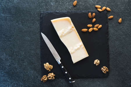 An appetizing solid cheese on a black plate on a gray stone background. Various types of cheeseの写真素材