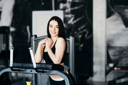 Beautiful sexy woman with a sports body in black and white sportswear trains in the gym. Sport activitiesの写真素材