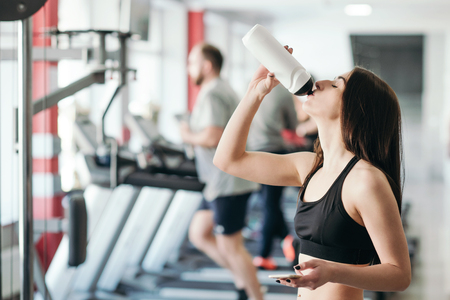 Beautiful sexy woman with a sports body in black and white sportswear trains in the gym. Sport activitiesの写真素材