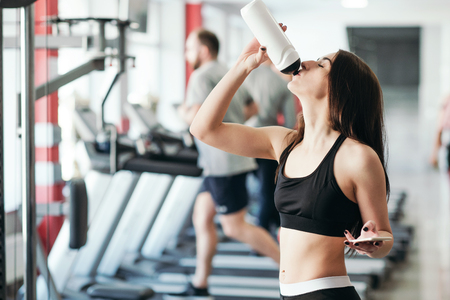 Beautiful sexy woman with a sports body in black and white sportswear trains in the gym. Sport activitiesの写真素材