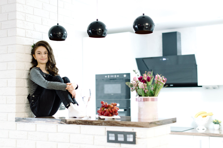 A cute little girl sits in the kitchenの写真素材