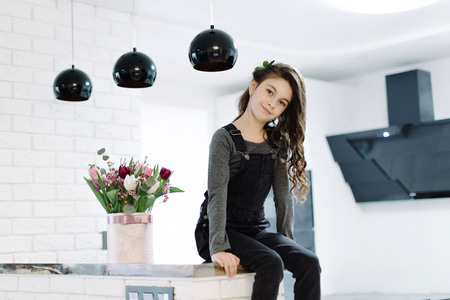 A cute little girl sits in the kitchenの写真素材