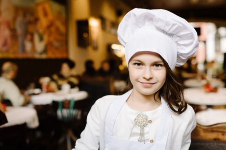 Feast day. Cute girl in a white cap is a chef's chefの写真素材