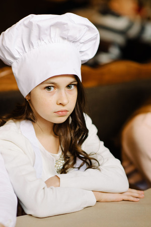 Feast day. Cute girl in a white cap is a chef's chefの写真素材