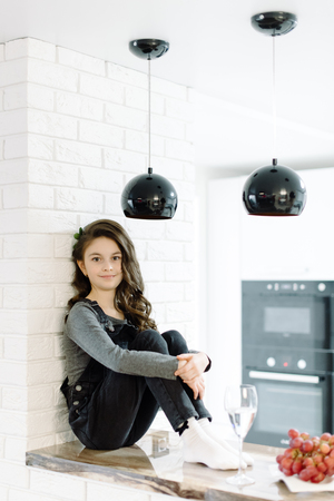 A cute little girl sits in the kitchenの写真素材