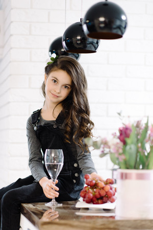A cute little girl sits in the kitchenの写真素材