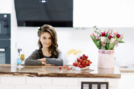 A cute little girl sits in the kitchenの写真素材