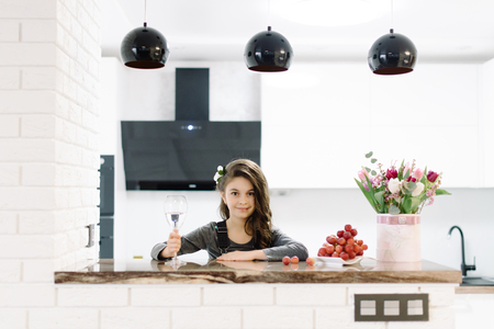 A cute little girl sits in the kitchenの写真素材