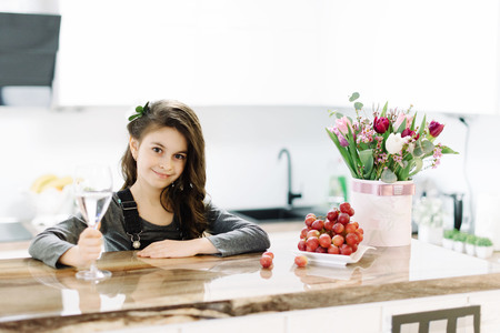 A cute little girl sits in the kitchenの写真素材