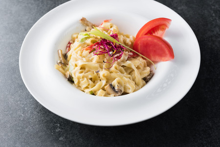 Italian paste of carbonaria with mushrooms with cream sauce on a white plate.の写真素材
