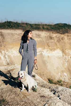 Young pretty girl walking a dog against a sandy pit.の写真素材